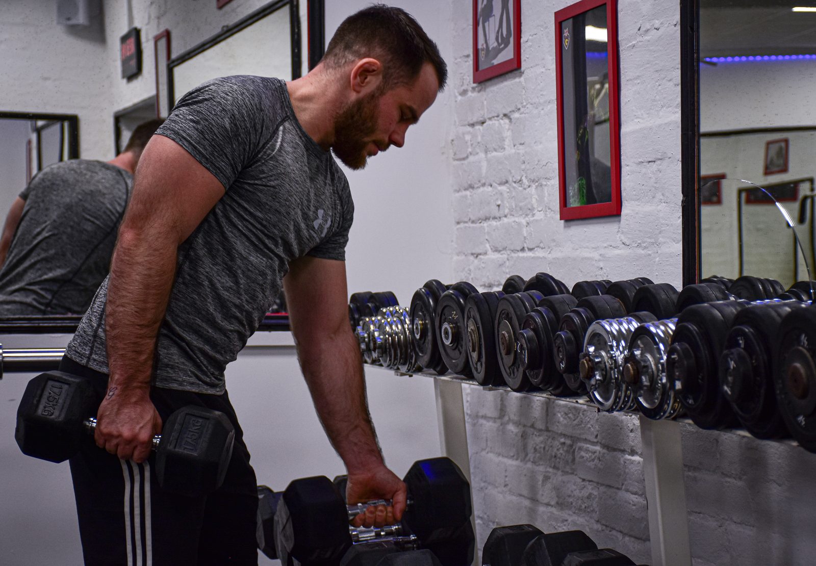 FitSync personal trainer selecting dumbbells from the rack before a training session
